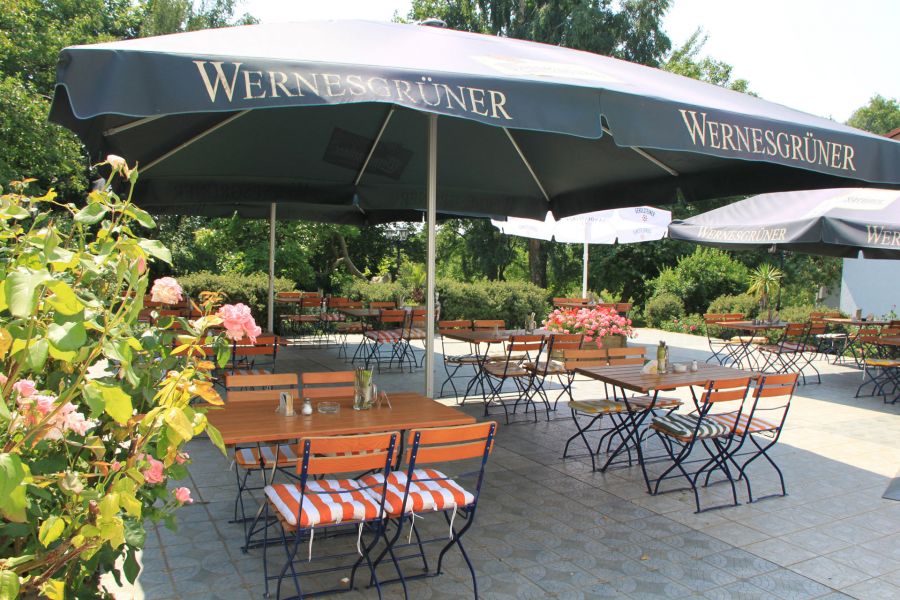 Biergarten im Gutspark mit offenen Sonnenschirmen